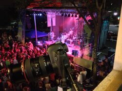 The digital SLR camera for Concert Cam aimed out an open window, with a band playing music on stage in the distance