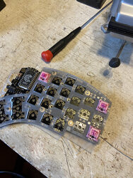 Key switches being fitted to the Kyria keyboard with a screw driver behind it
